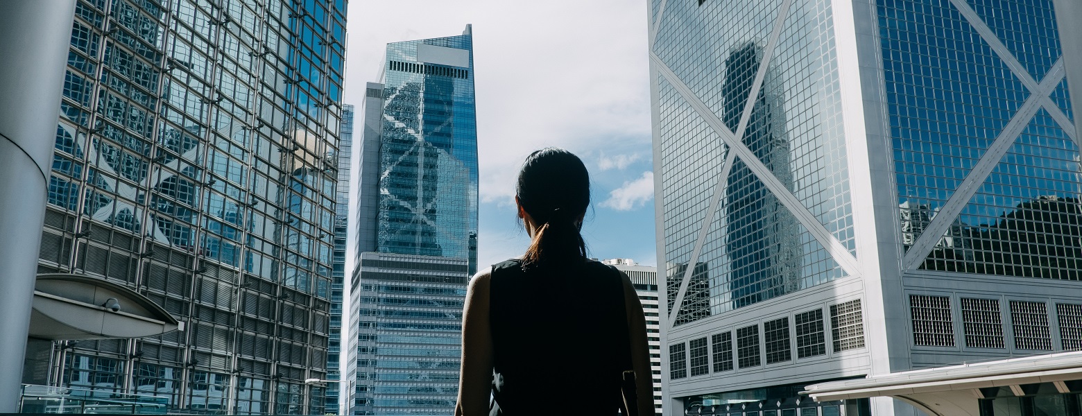 Female businesswoman standing in front and facing two high-rise buildings